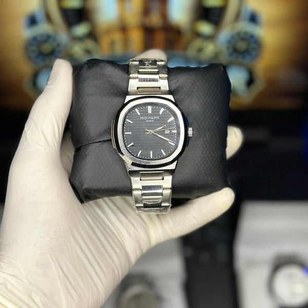 Silver watch held by a gloved hand with a blurred background